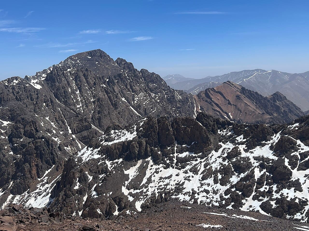Sommet rocheux du Toubkal parsemé de névés sous un ciel bleu, Haut Atlas