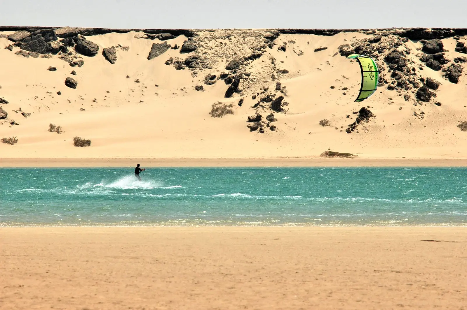 Un kitesurfeur devant la dune de sable qui borde la lagune de Dakhla